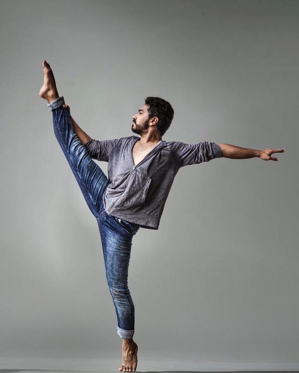 Focused male athlete in a warrior yoga pose in a modern studio.